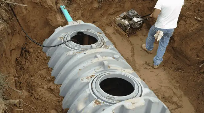 Septic tank installation showing a technician compacting soil around a new poly septic tank in an excavation pit in Fort Worth, TX